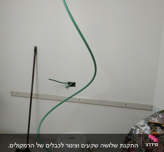צינור ירוק יוצא מקיר עם כלי עבודה